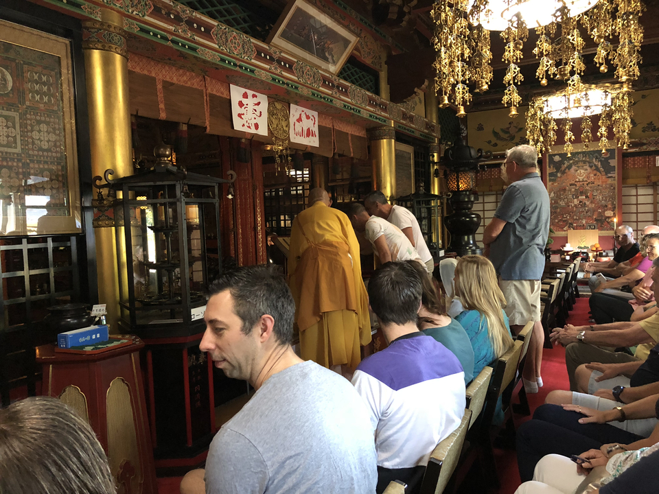 People observing a traditional ceremony inside a temple.
**French translation:**
Des personnes observant une cérémonie traditionnelle à l'intérieur d'un temple.