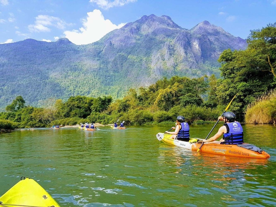 Des gens faisant du kayak dans une rivière entourée de montagnes.