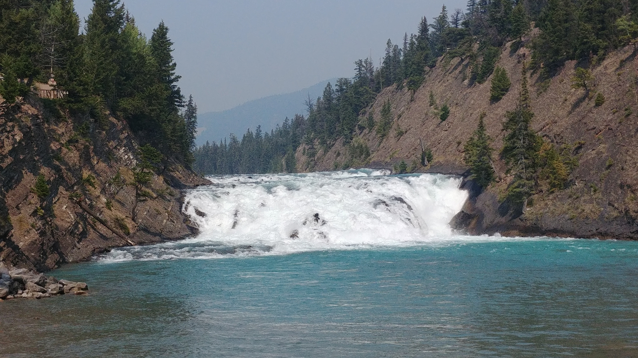 Cascade avec de l'eau bleue entourée de falaises.