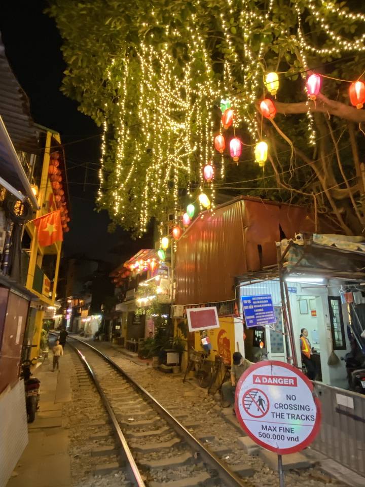 Voie ferrée animée avec lanternes la nuit.