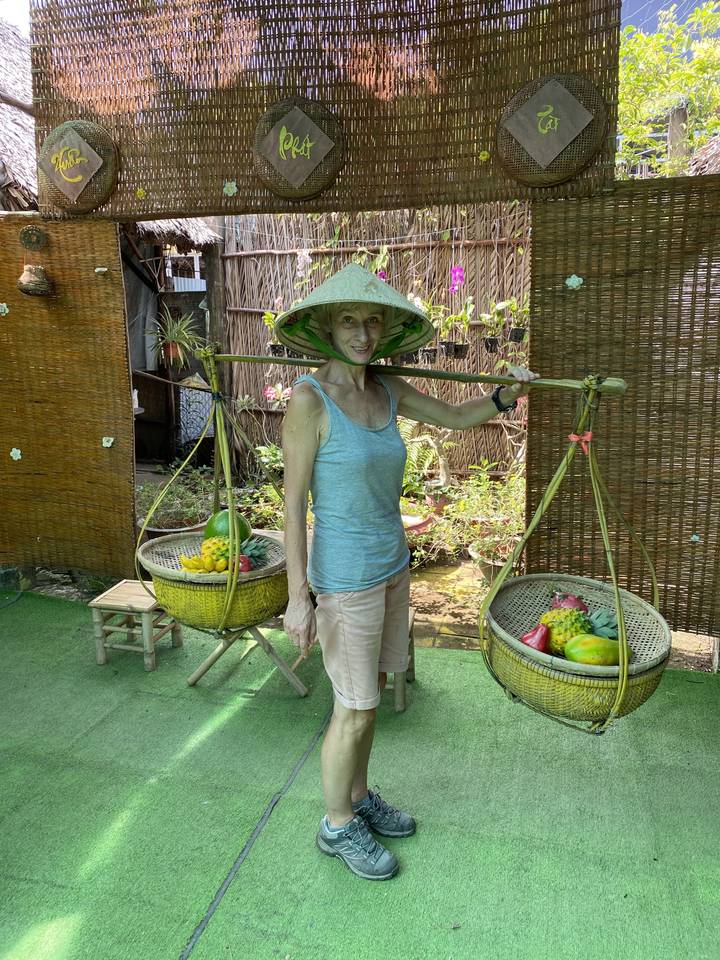 Femme locale avec un panier de fruits portant un chapeau conique.