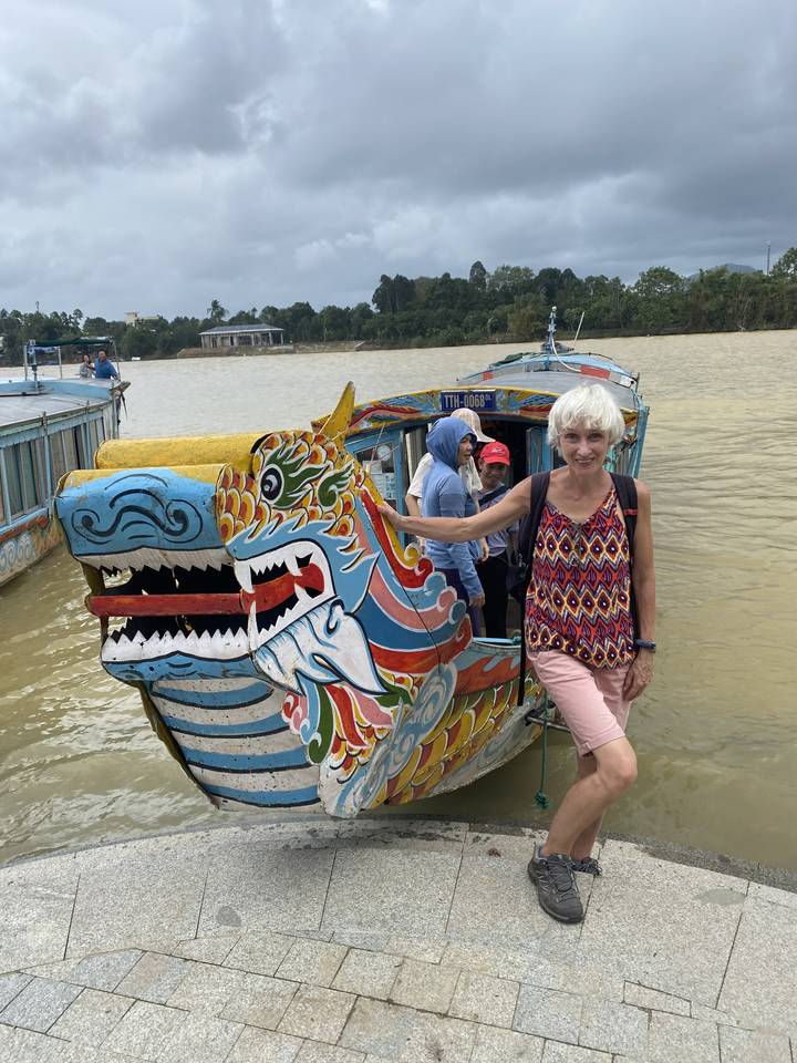 Femme debout à côté d'un bateau-dragon coloré.