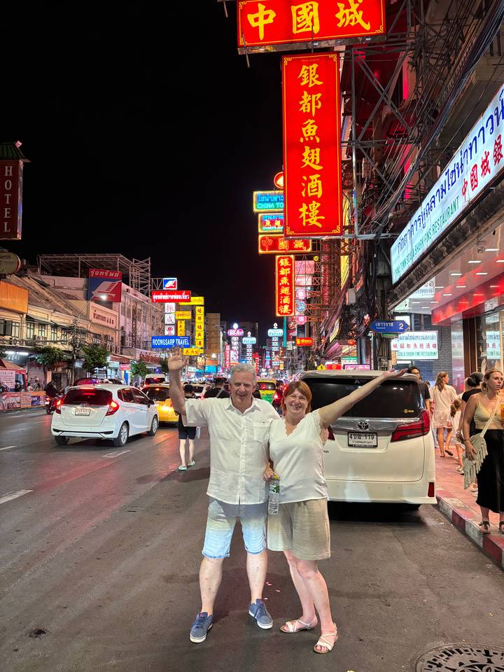 Night market with neon signs and people walking around.