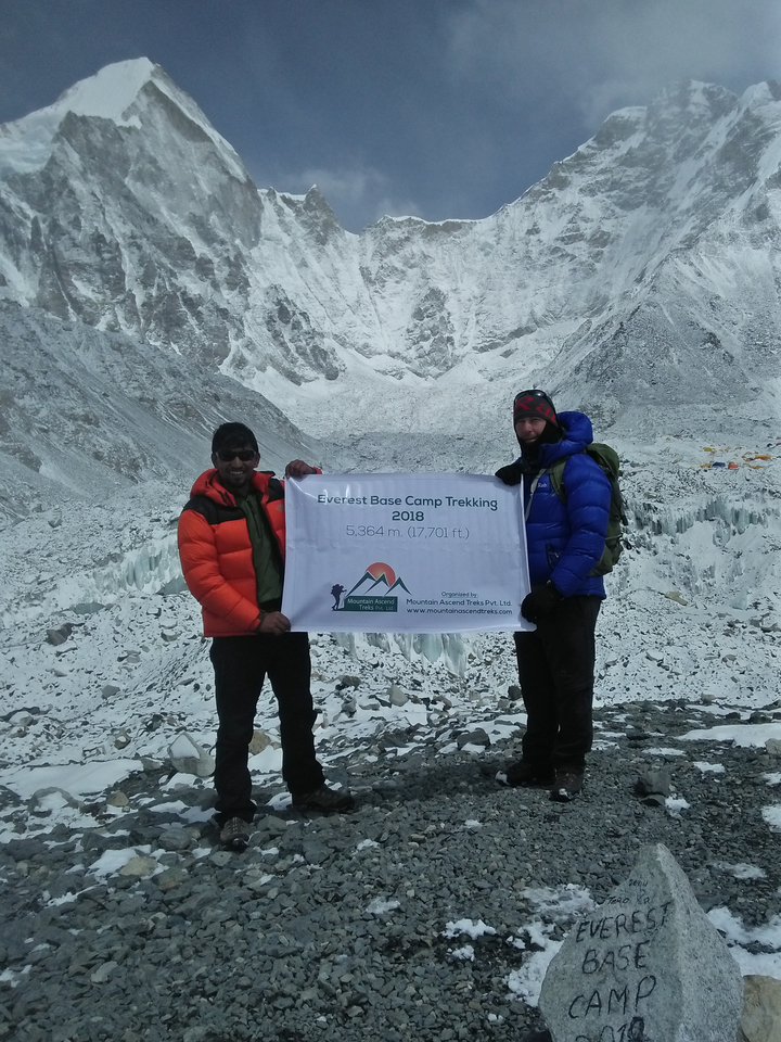 Two people holding a sign at Everest Base Camp.