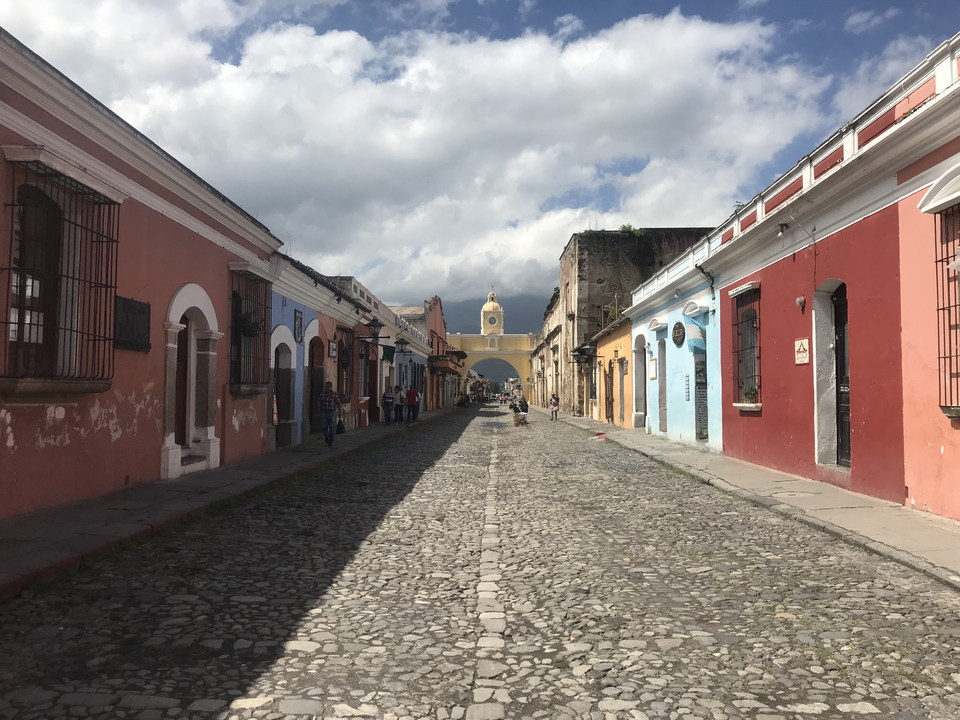 Rue colorée à Antigua, Guatemala avec route pavée et arcade.