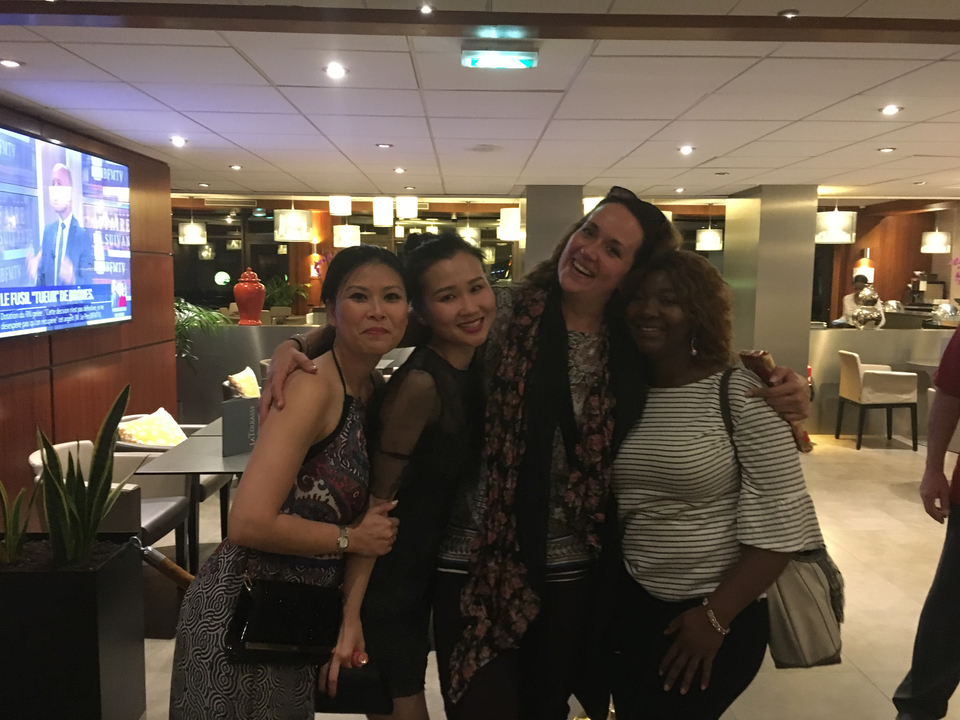 Quatre femmes souriantes à l'intérieur, avec des lampes et de la décoration visibles.