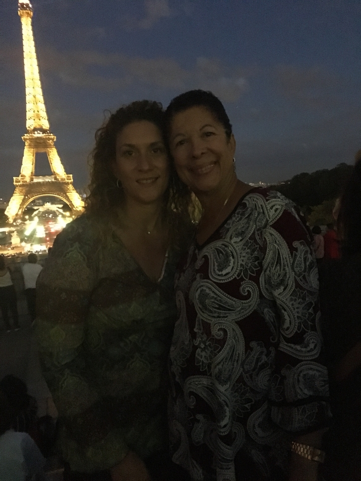 Deux personnes avec la tour Eiffel faiblement visible en arrière-plan la nuit.