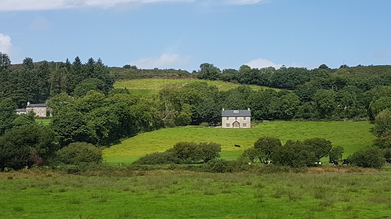 Champs verts avec une petite maison au centre.