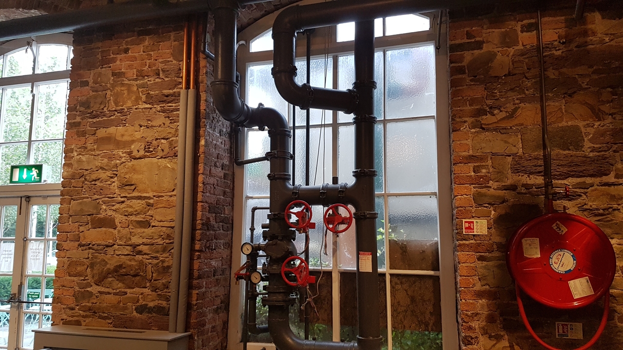 Tuyaux industriels contre un mur de briques.