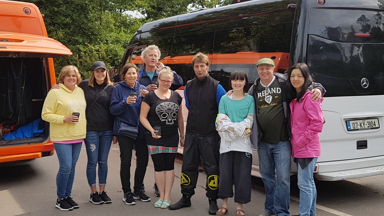 Groupe de personnes posant devant un bus de tourisme.