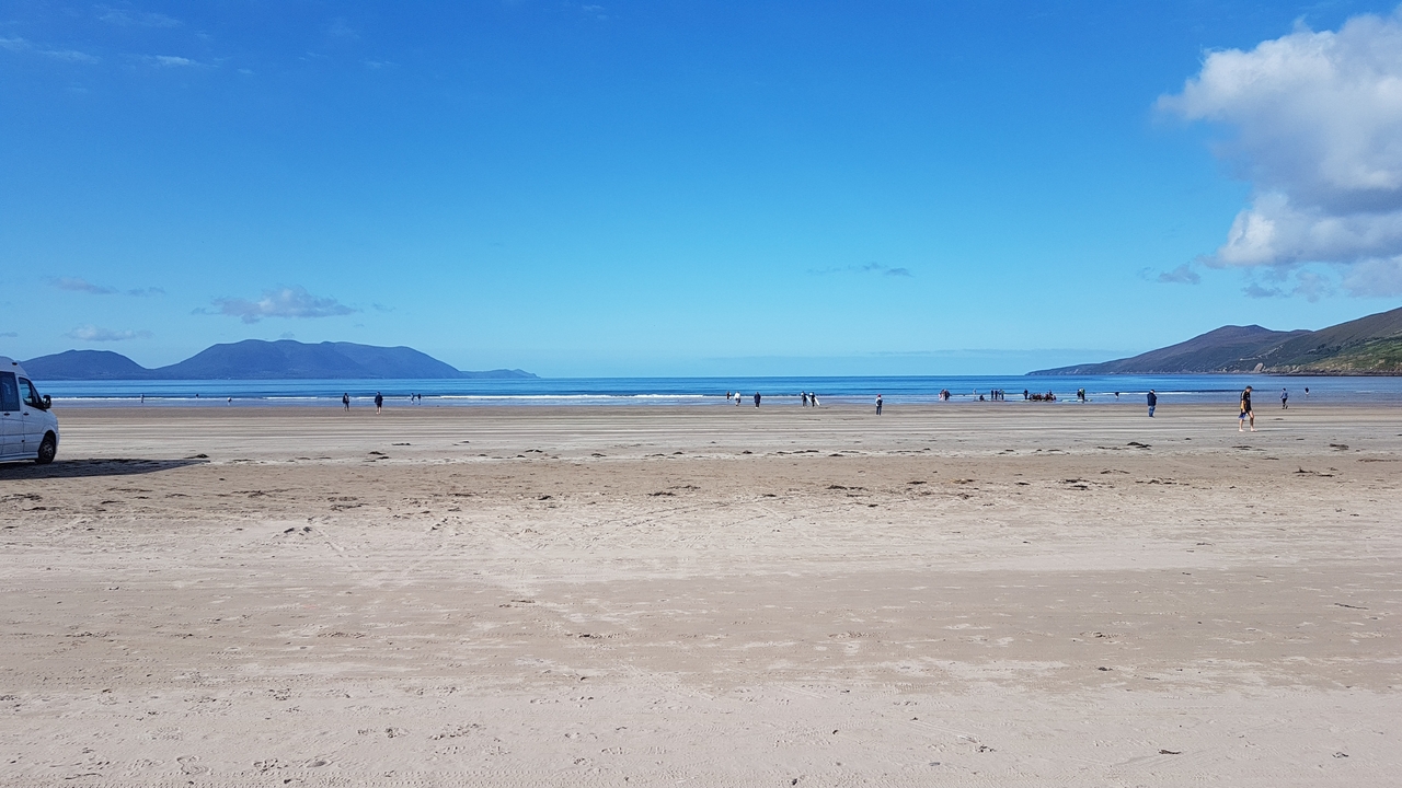 Plage de sable avec montagnes lointaines et ciel.