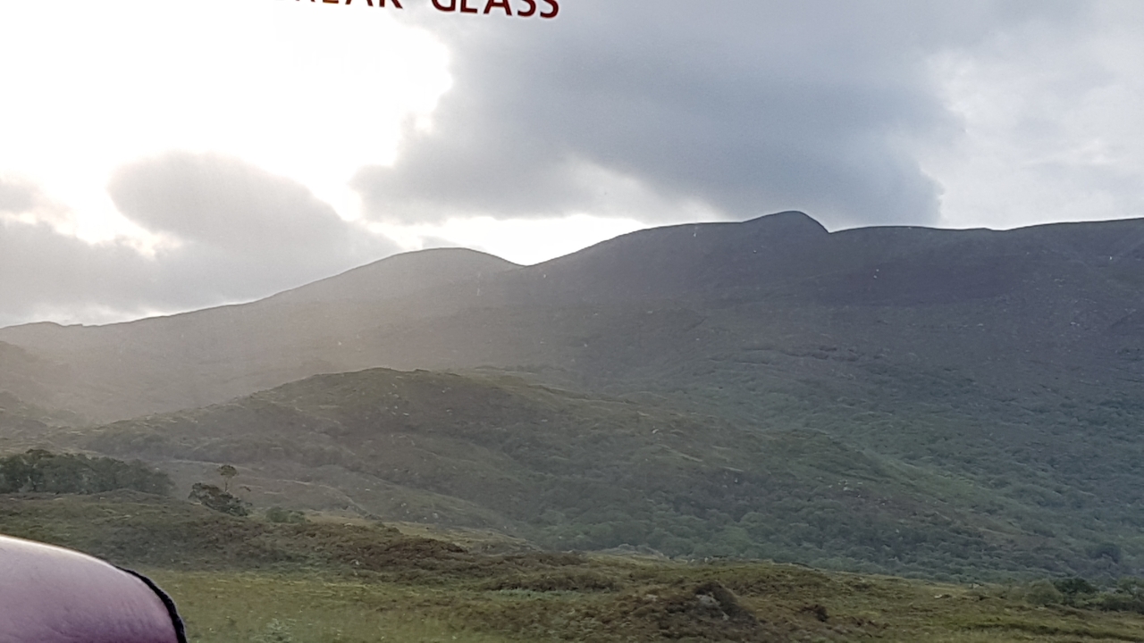 Paysage avec collines et lumière du soleil filtrant à travers les nuages.