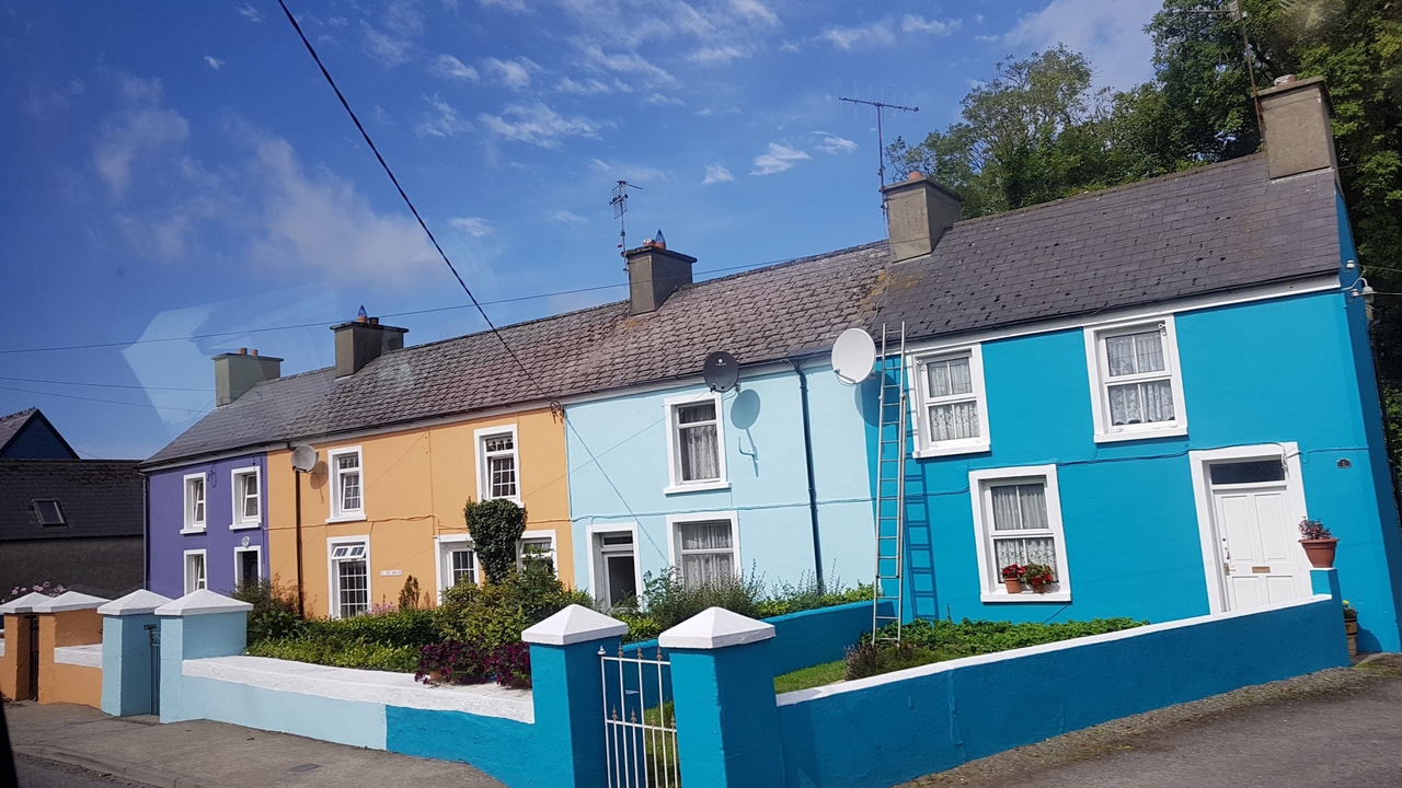 Rangée colorée de maisons sous un ciel bleu clair.