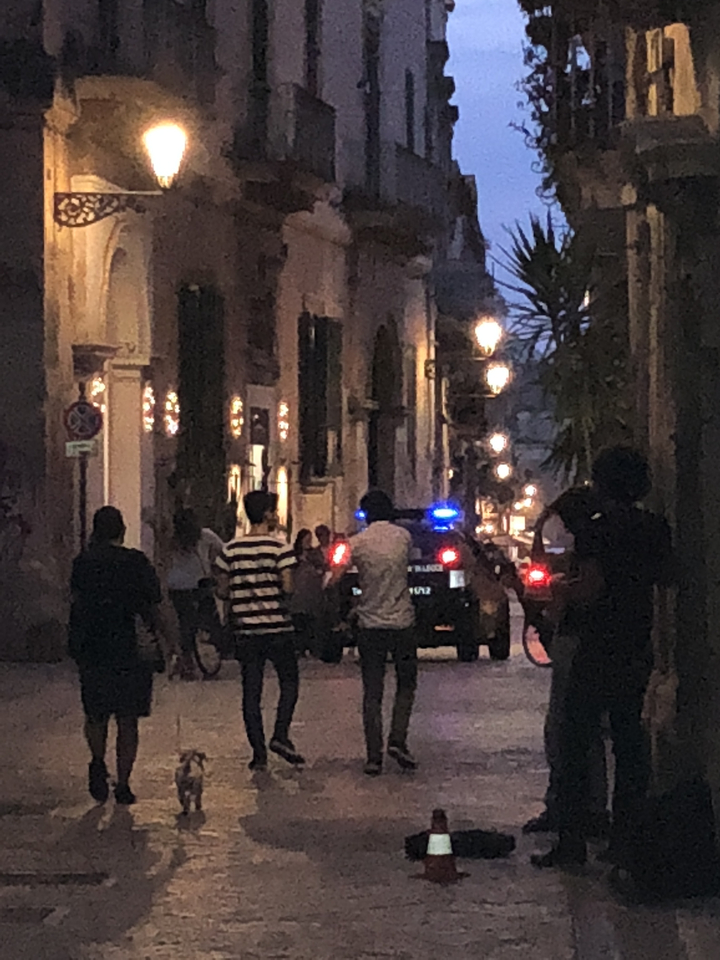 Une scène de rue la nuit avec des gens et une voiture de police.