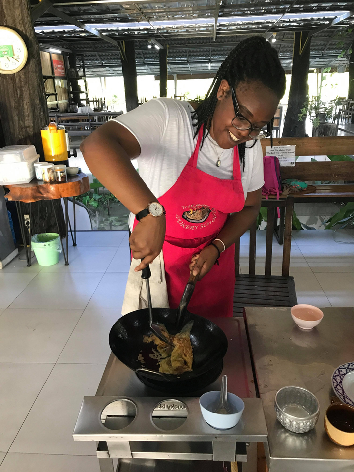 A person cooking with a pan at a cooking school.