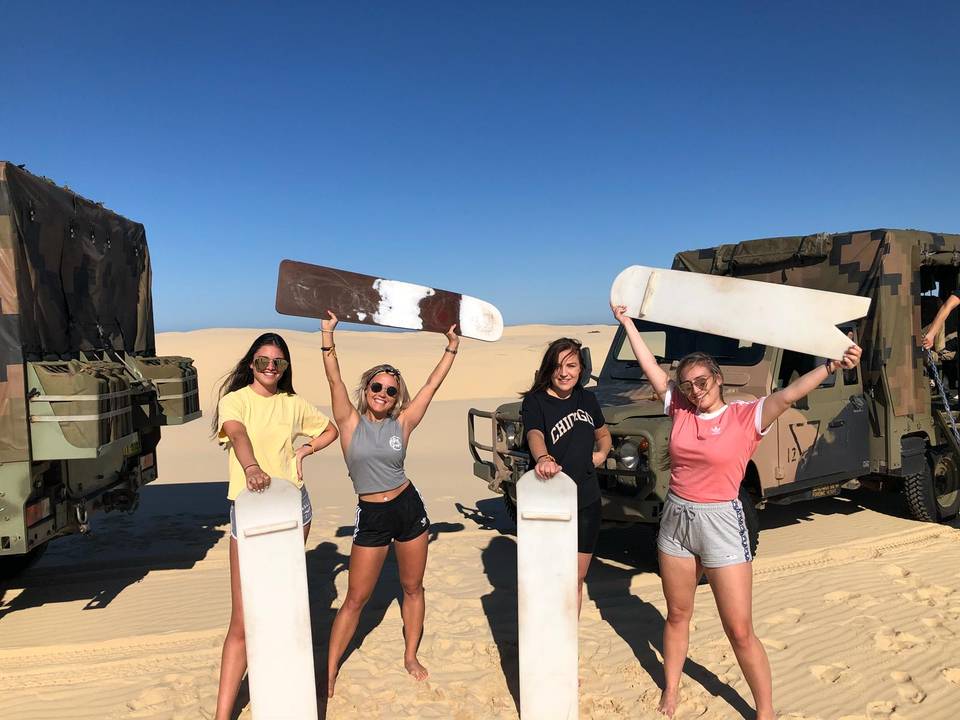 Group with sand boards in a sandy landscape.