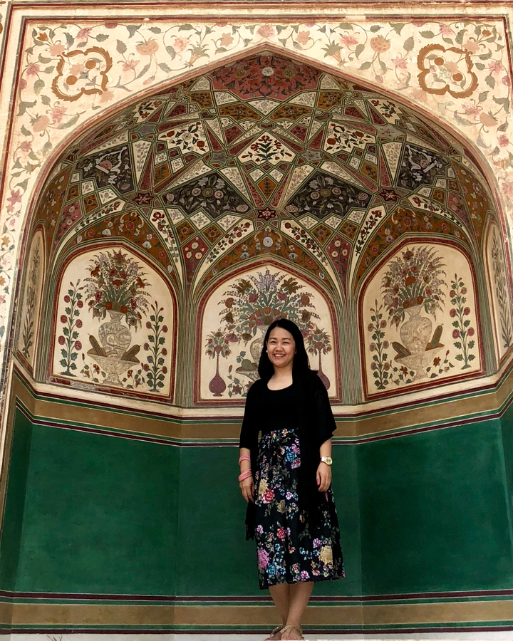 Femme se tient debout devant une arche colorée décorée.