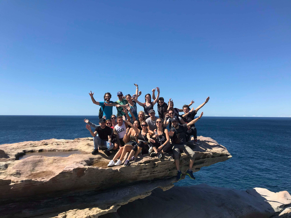 Group of people posing on a rocky ledge by the ocean.