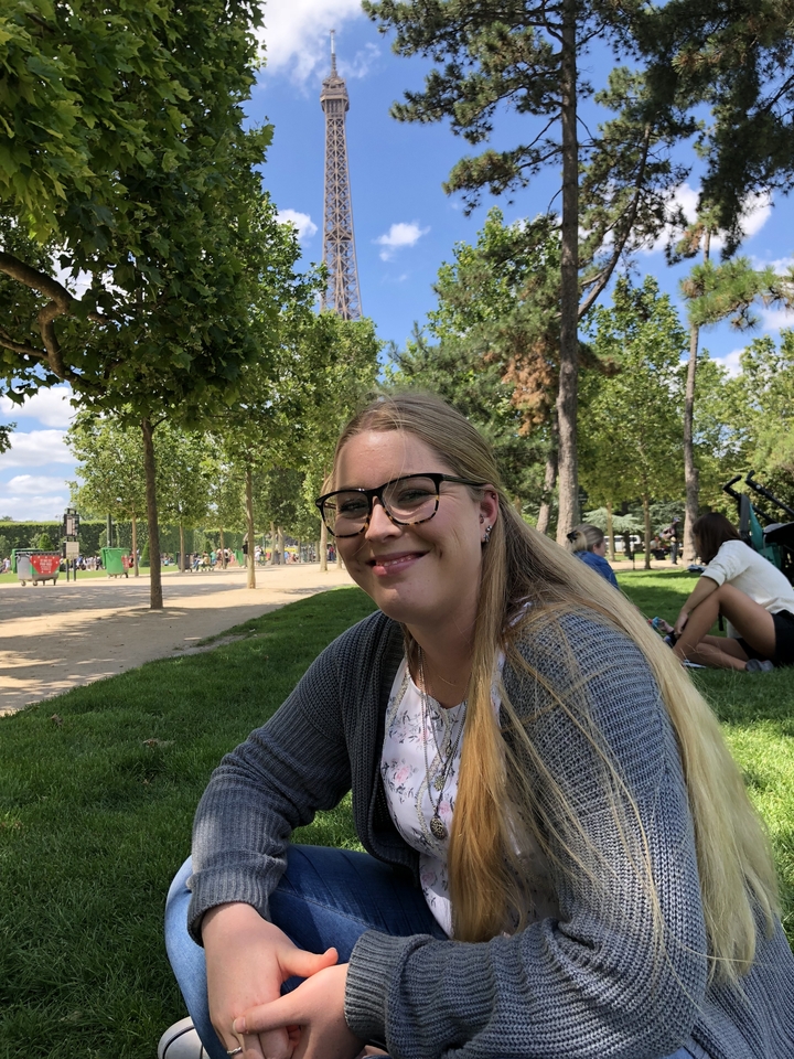 Femme souriante assise sur l'herbe dans un parc.