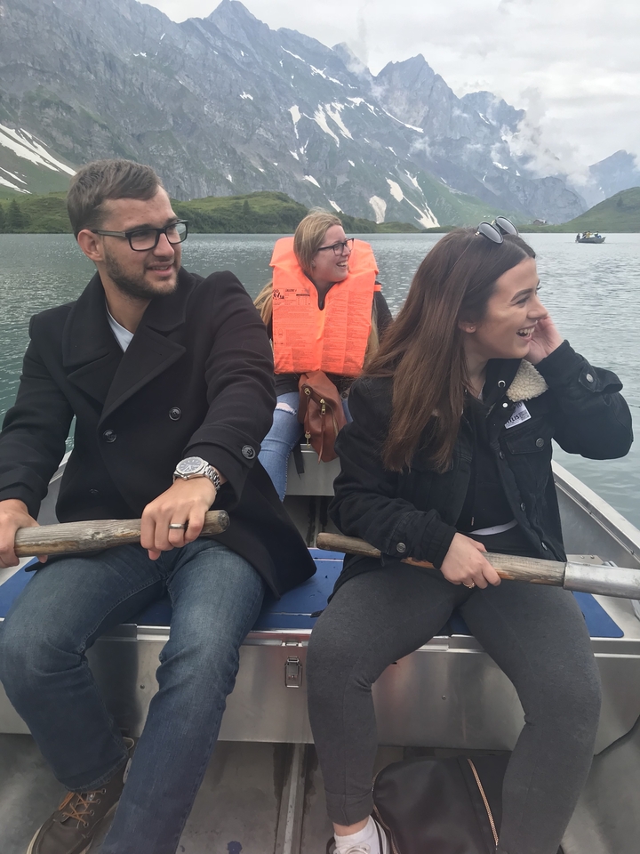 Trois personnes ramant dans un bateau sur un lac.