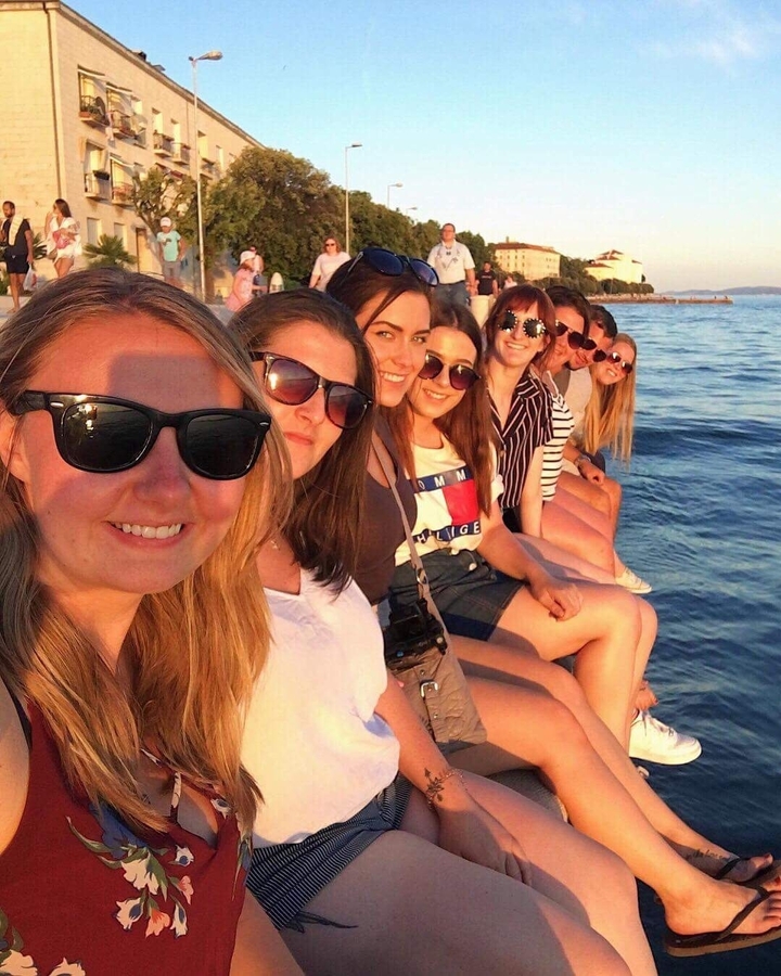 Groupe de personnes assises sur un quai au coucher du soleil.