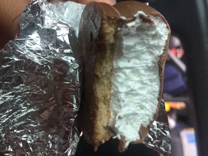 Close-up of a cream-filled cookie with a foil background.