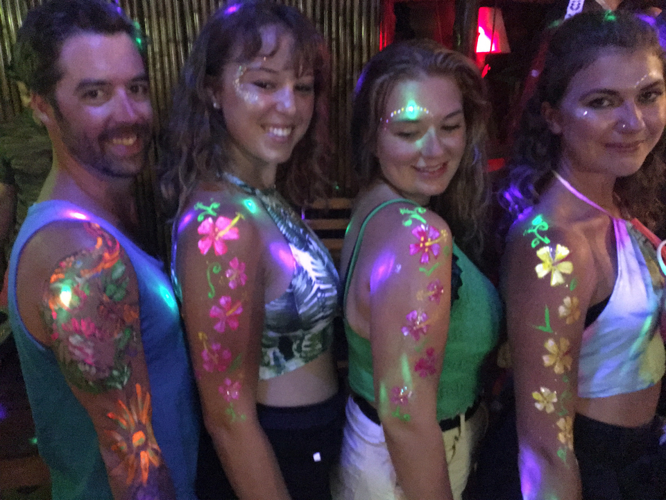 Des personnes avec de la peinture fluorescente qui prennent la pose sur un fond sombre.