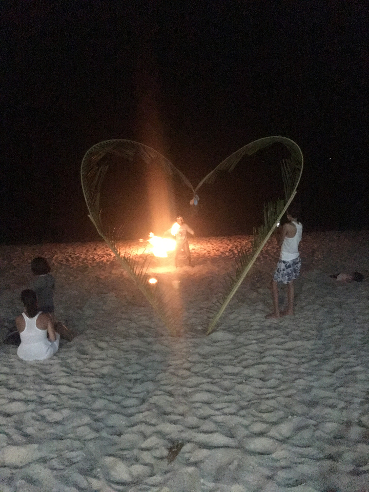 Des gens sur une plage la nuit avec un spectacle de feu.