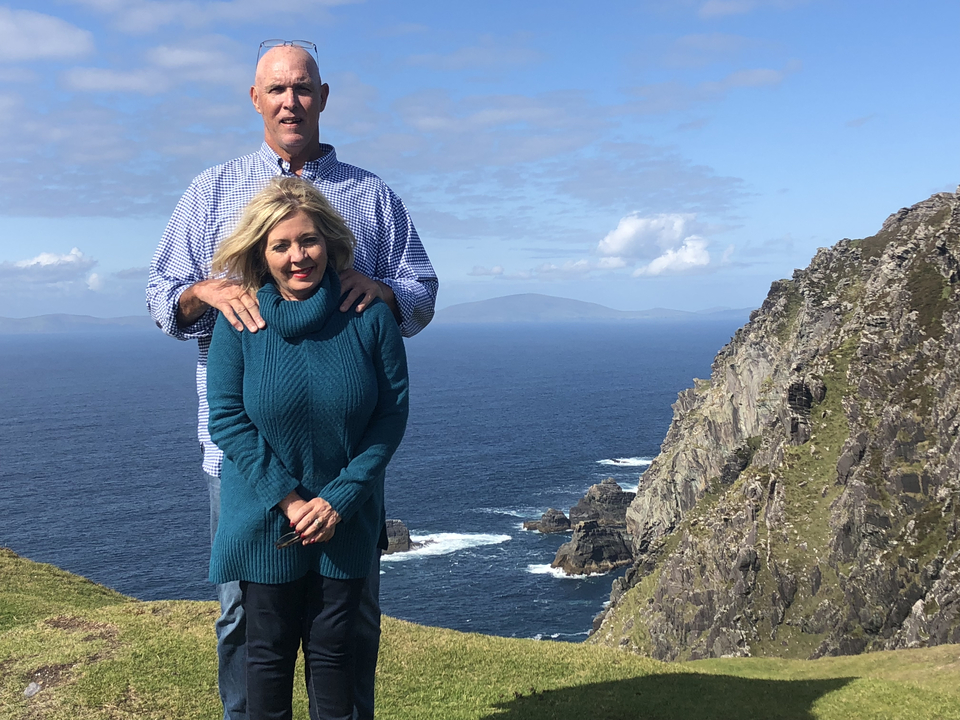 A couple posing against a backdrop of cliffs and sea.