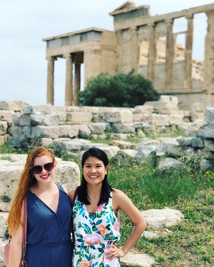 Two women posing in front of ancient ruins.
