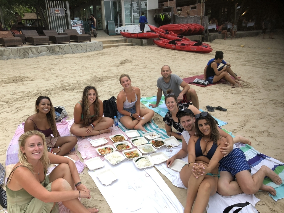 Groupe de personnes faisant un pique-nique sur le sable près de kayaks.