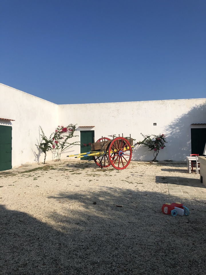 Cour italienne traditionnelle avec une charrette colorée.