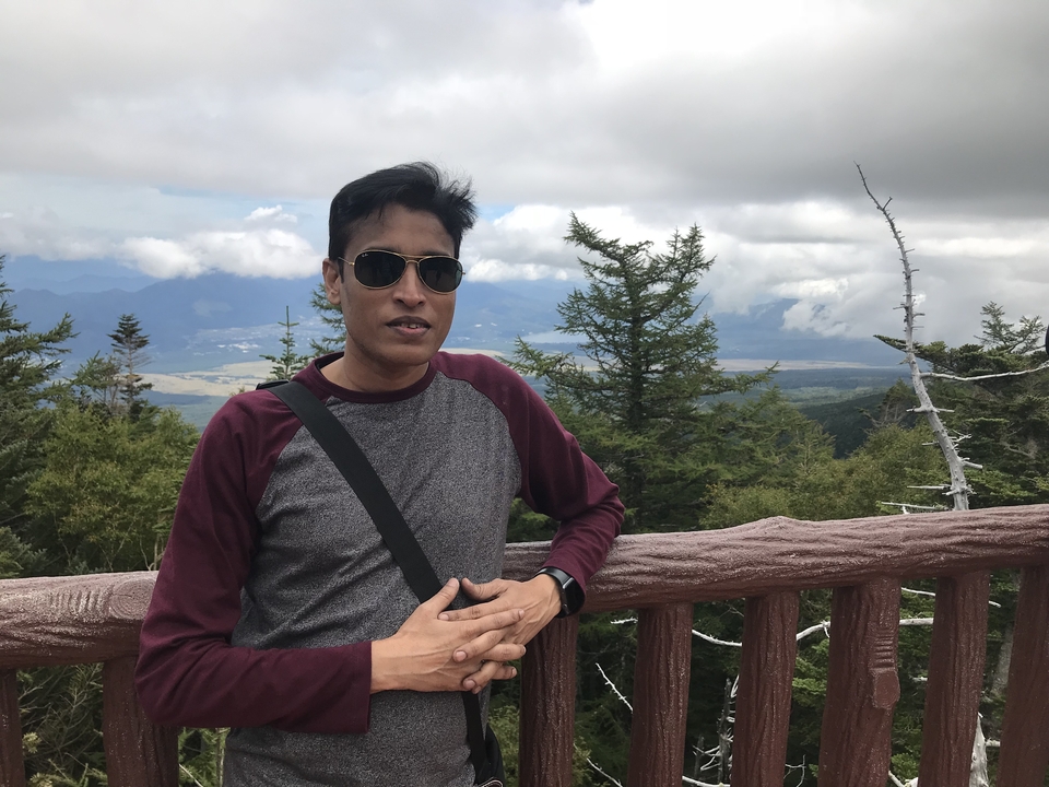 Homme posant sur un balcon avec vue panoramique sur les montagnes.