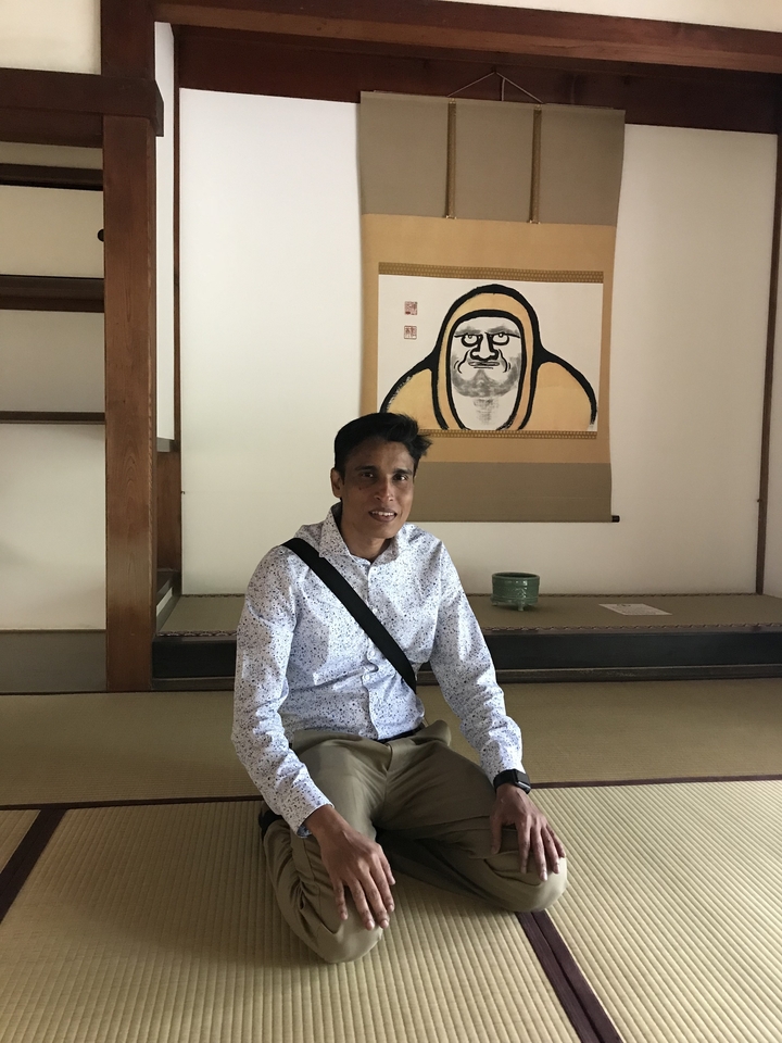 Homme assis dans une pièce japonaise traditionnelle avec une peinture.