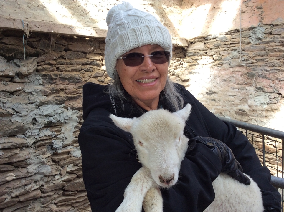 Femme tenant un agneau dans un cadre rustique.