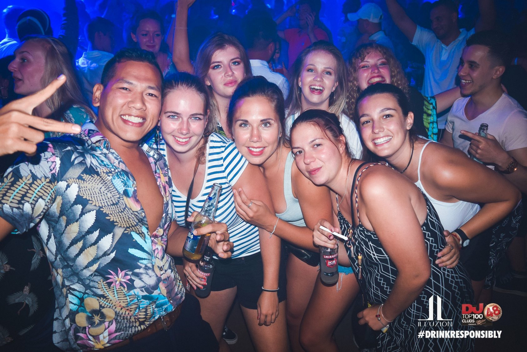 A group of people enjoying nightlife with colorful lights in the background.