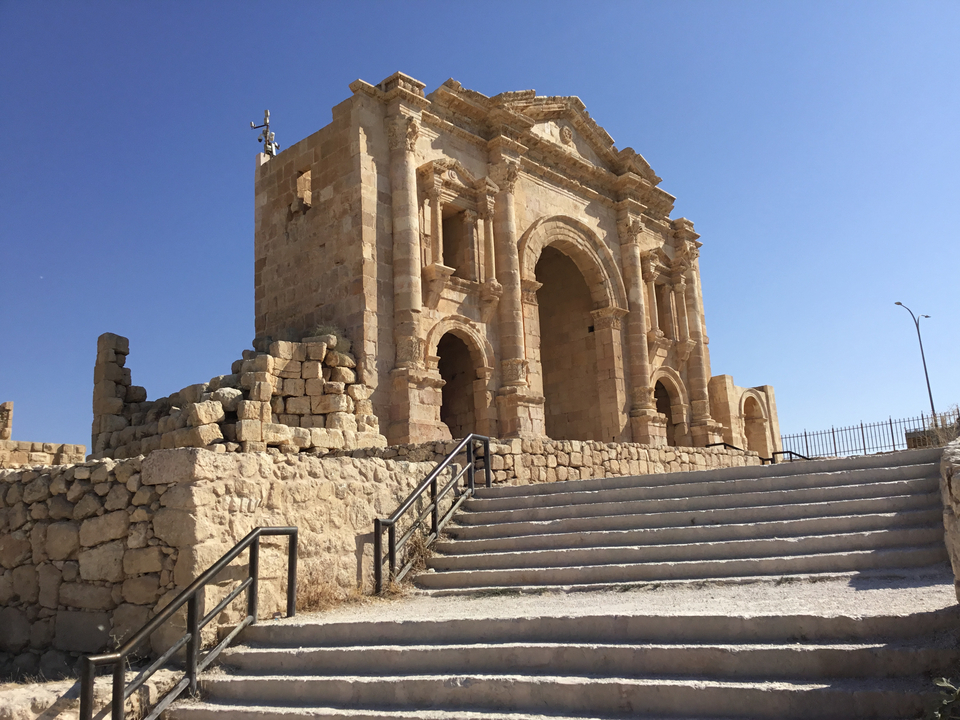 Portail romain antique avec arches et marches.