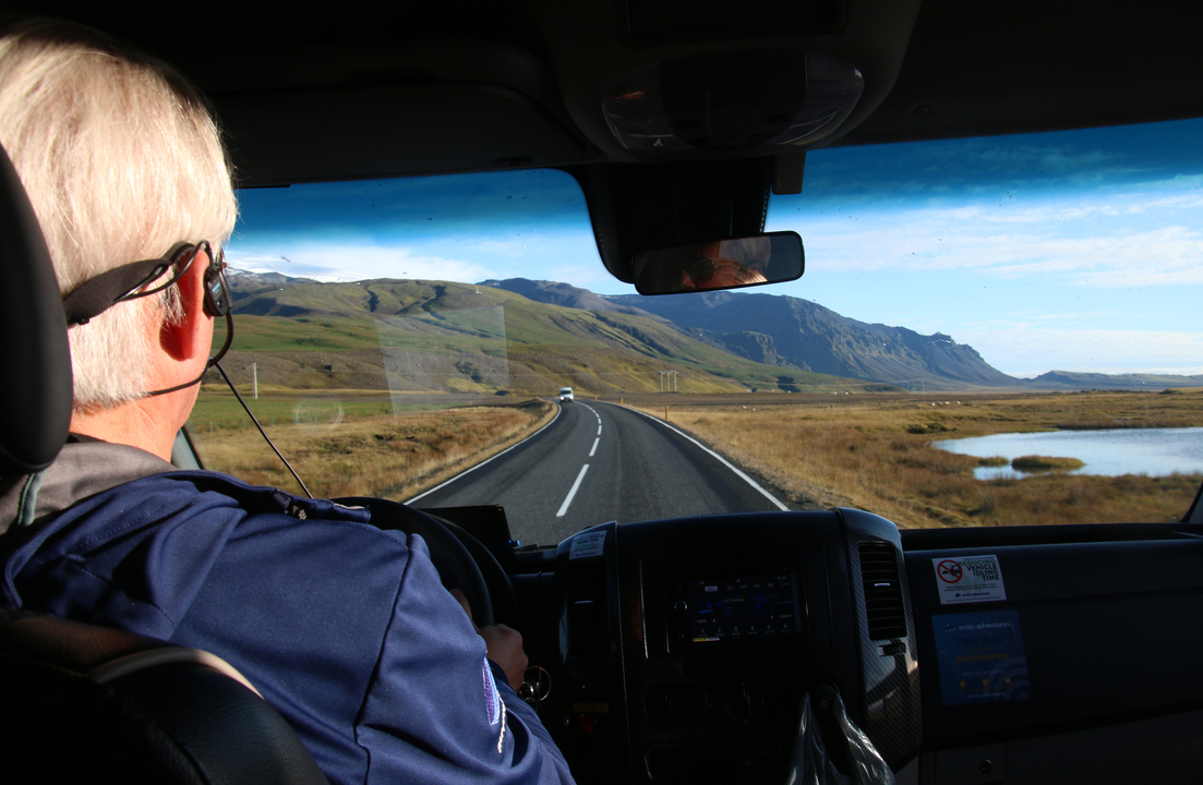 Vue depuis un véhicule roulant sur une route panoramique avec des montagnes en arrière-plan.