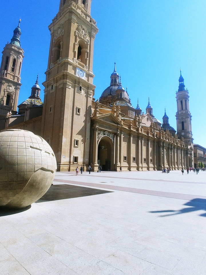 Historical building with a spherical sculpture in front.