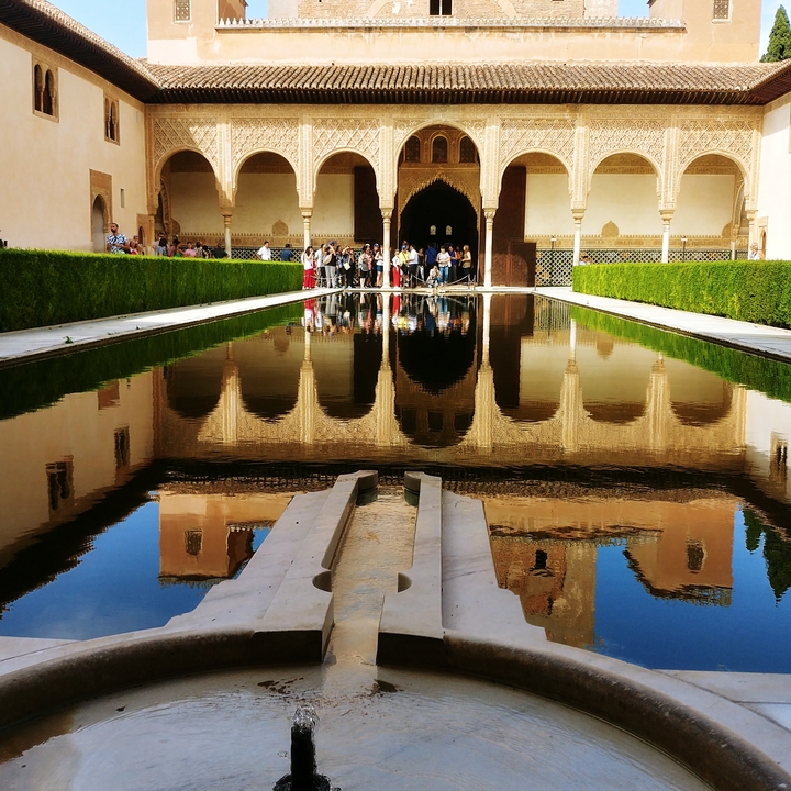 Alhambra palace with reflective pool and tourists.