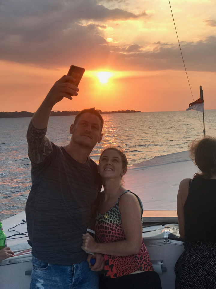 Couple taking a selfie during sunset over the ocean.