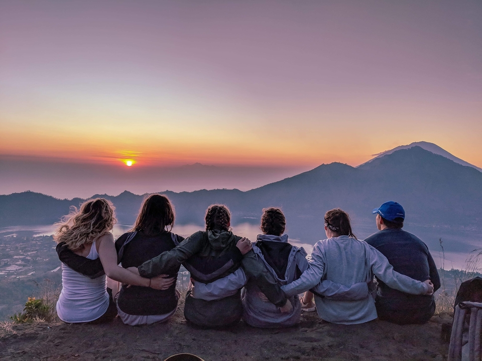 Groupe regardant un lever de soleil sur un paysage montagneux.