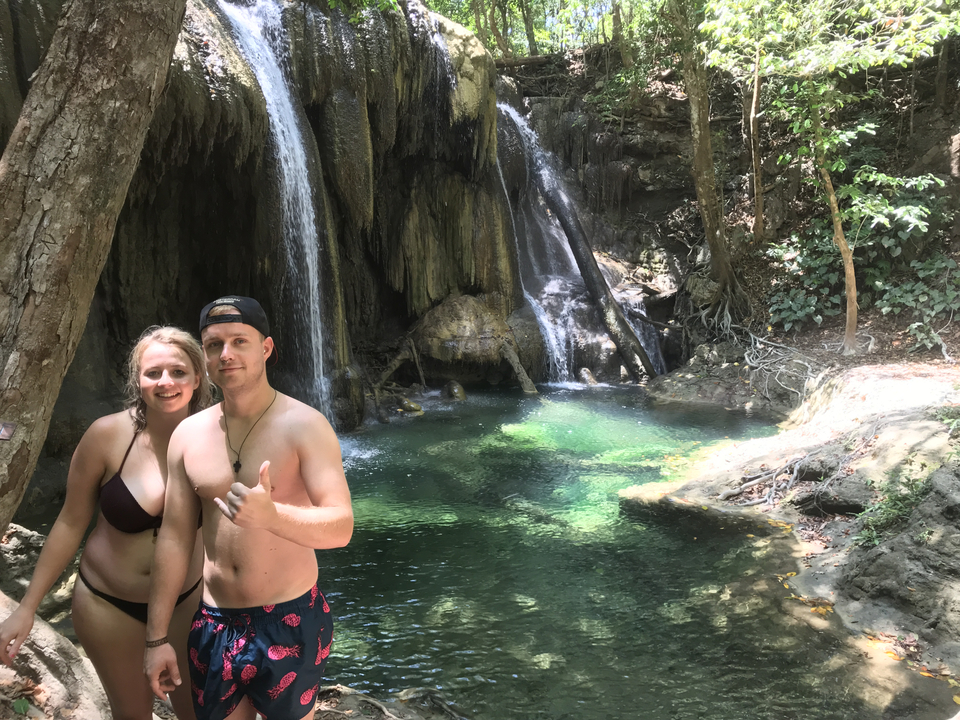 Couple posing in front of a waterfall in the jungle.