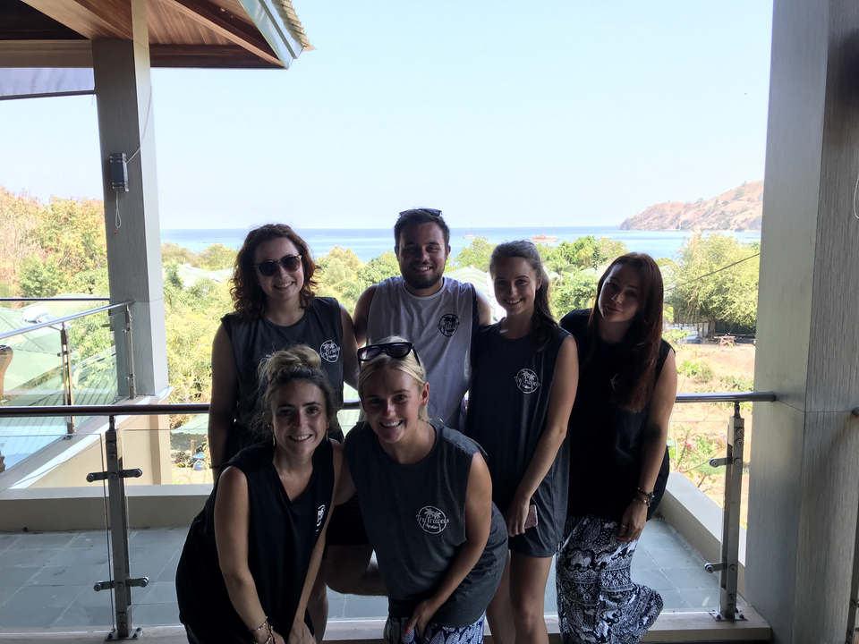 Group of people posing on a balcony overlooking the sea.