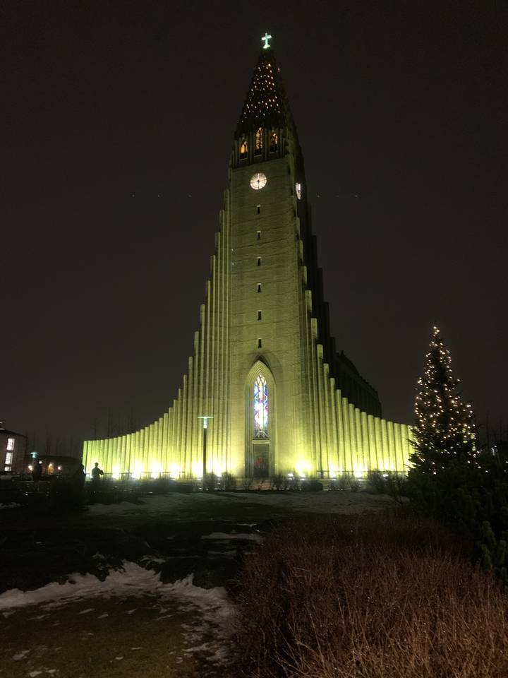 Église illuminée la nuit avec de la neige au sol.