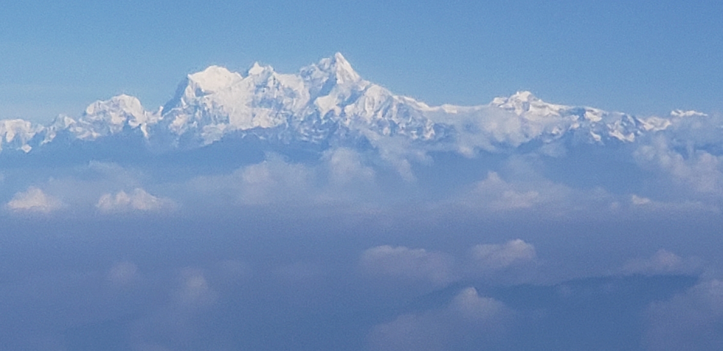 Close view of a towering snow-covered mountain massif under clear skies.