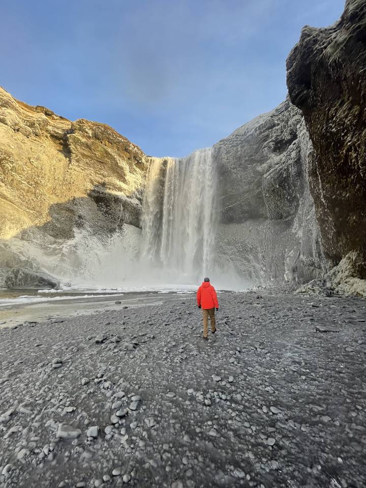 Man approaching a large waterfall.