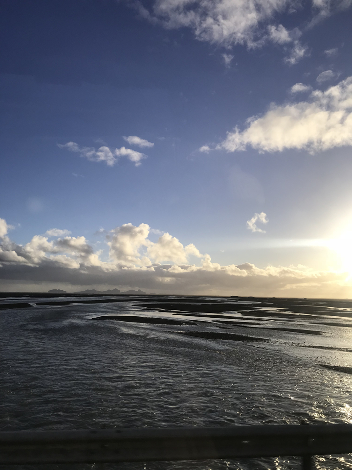 Cloudy sky over a vast landscape with water.