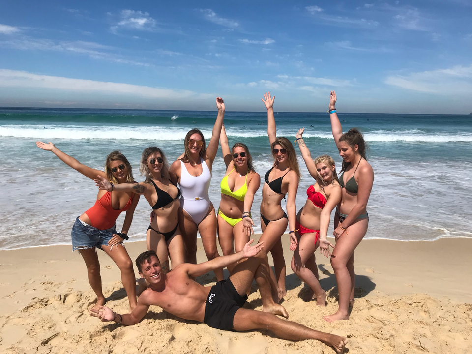 Group of people posing on a beach with the ocean behind.