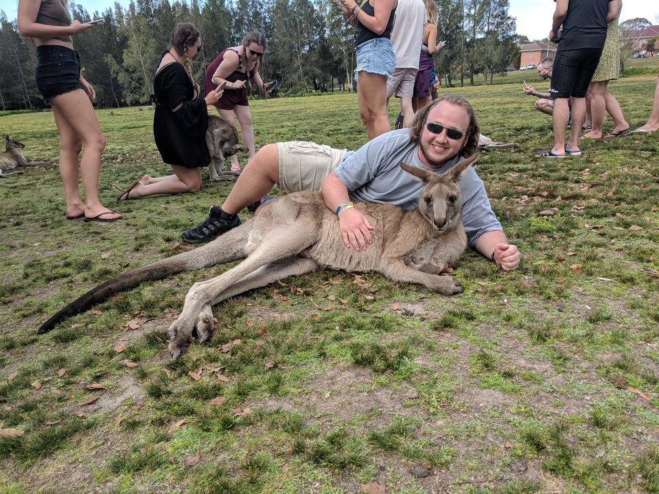 Man lying on grass with a kangaroo.